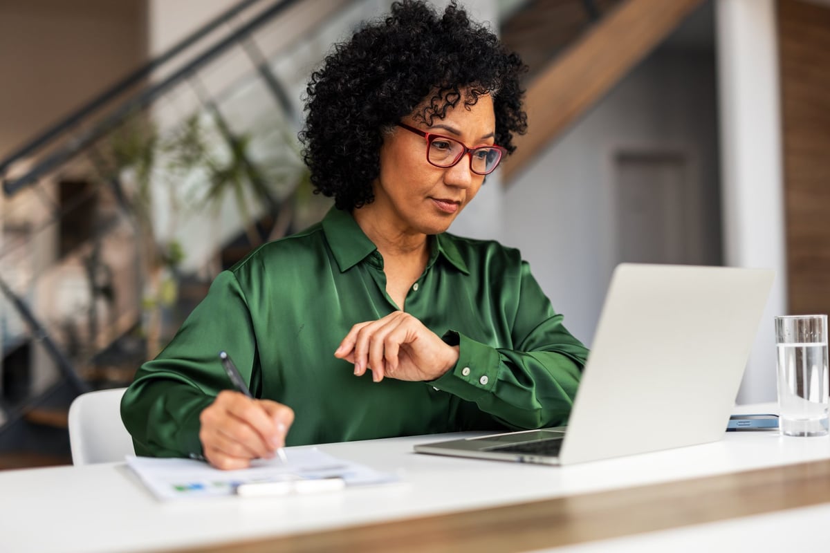 Professional woman concentrating on a desk project with a laptop in a bright, modern workspace