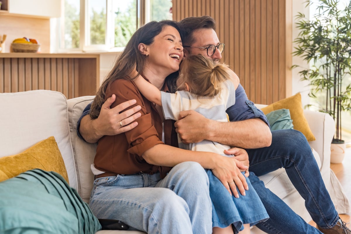 Happy young family with a child enjoying their new home, unpacking and relaxing together