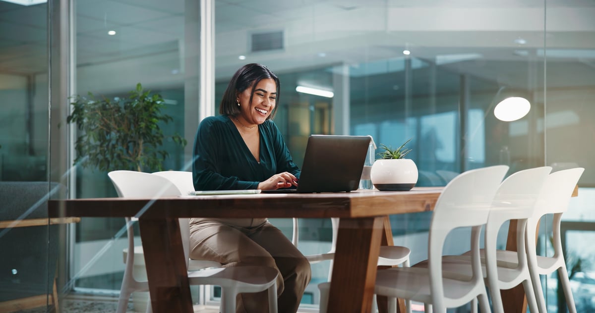 Smiling business woman working on a laptop in a bright modern office, planning a project