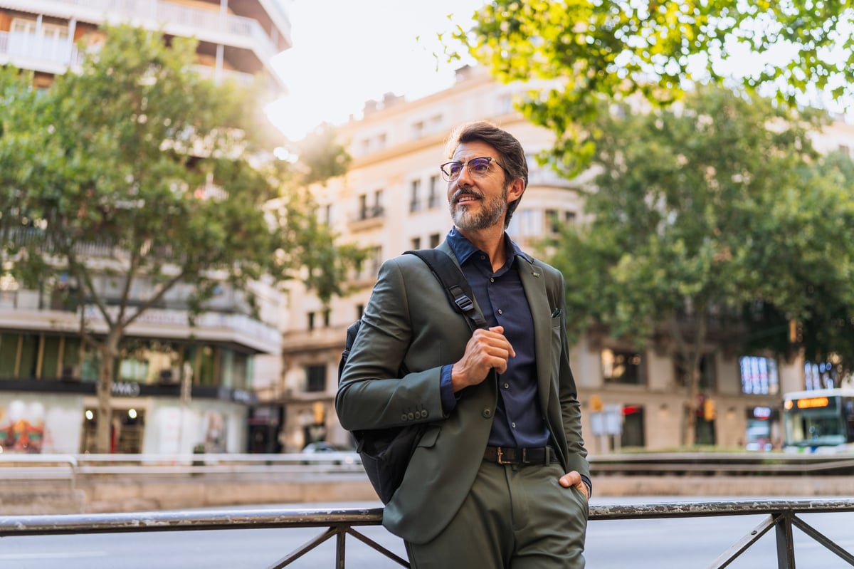 Stylish middle-aged man in suit standing on city street at sunset. Concept of business, ambition, urban lifestyle