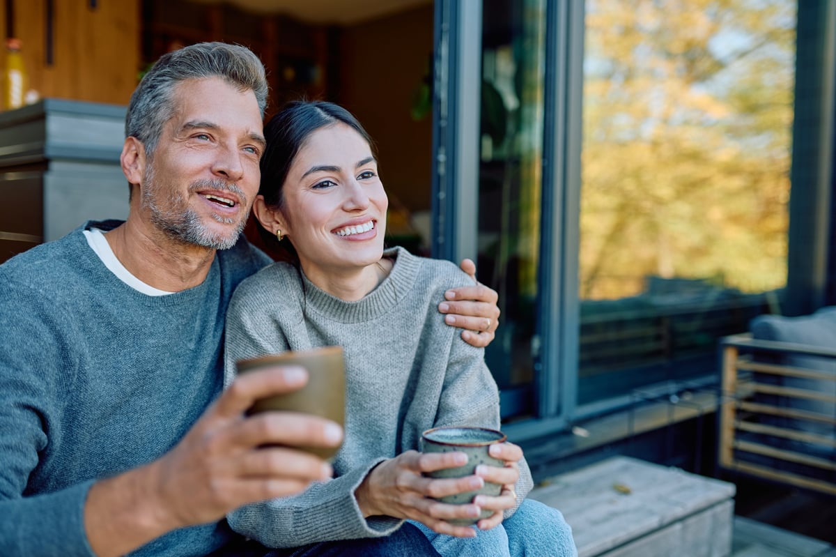 Happy couple enjoying coffee on their home terrace on a sunny day