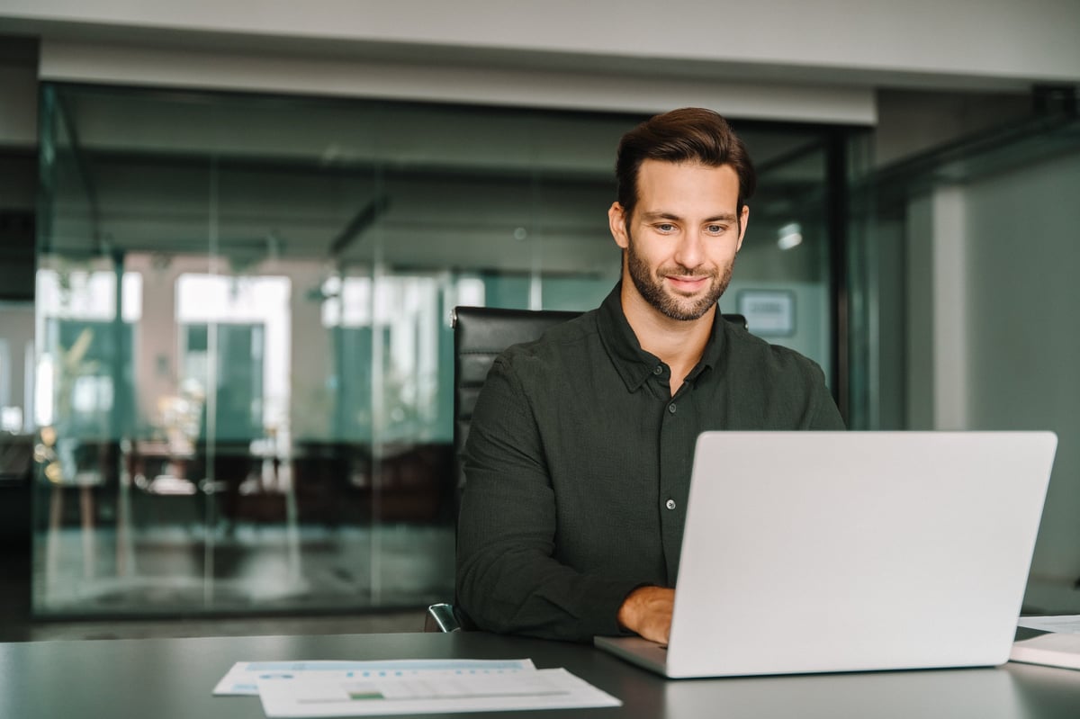 Young latino business man working on a laptop at a desk in a modern office