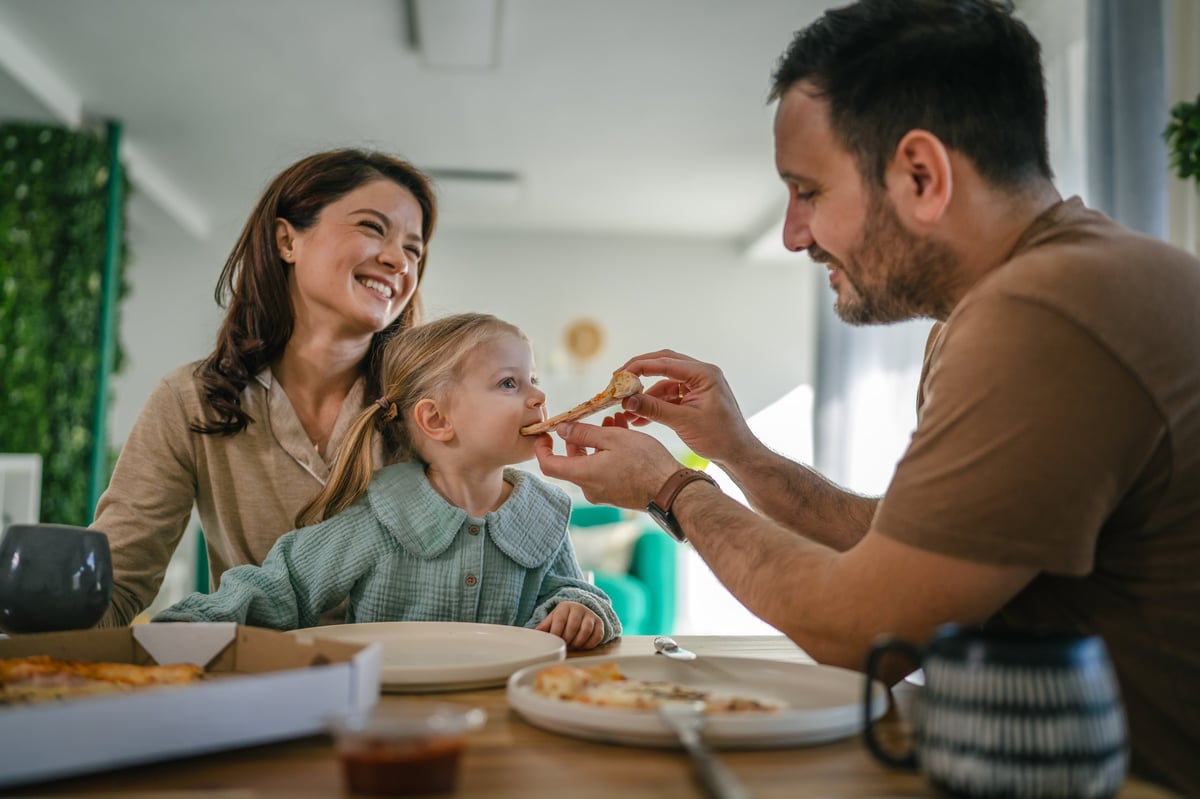 Father feeding his daughter during a happy family meal at home