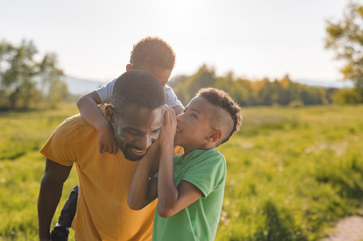 Single father sharing joyful moments with his sons in a park at sunset