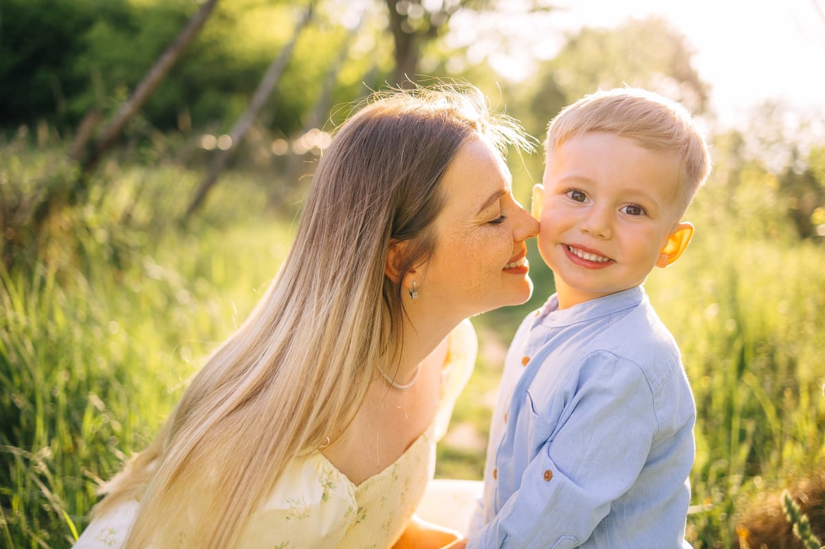 Mother and young son sharing a tender moment in a sunlit meadow